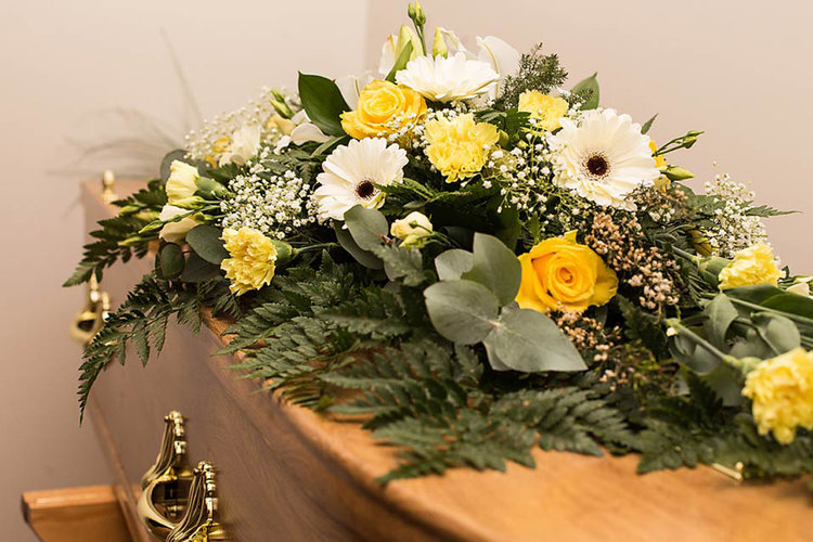 An arrangement of yellow and white flowers on a coffin